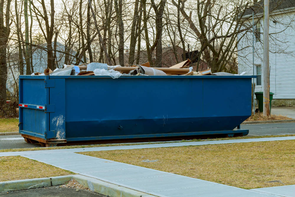 A bin filled with junk in the driveway of a home